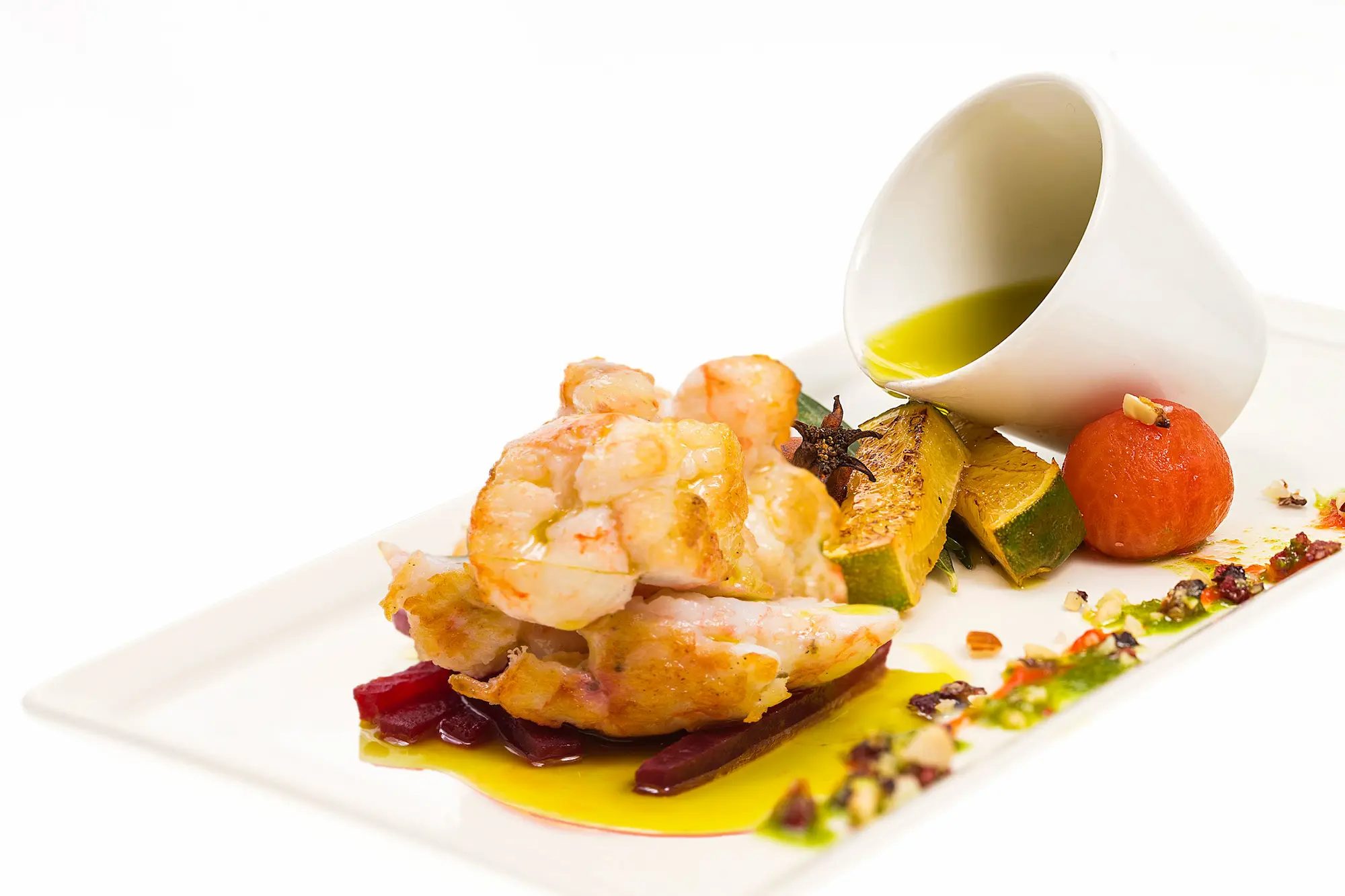 Shot of scampi tails in olive oil with zucchini and tomato, on white backgrou